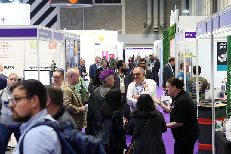 Busy crowds of people in an aisle at The Print Show trade exhibition at the NEC conference centre in Birmingham